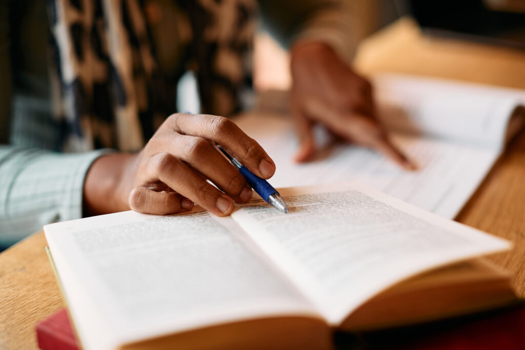 Close-up of female student learning from books in a library.
