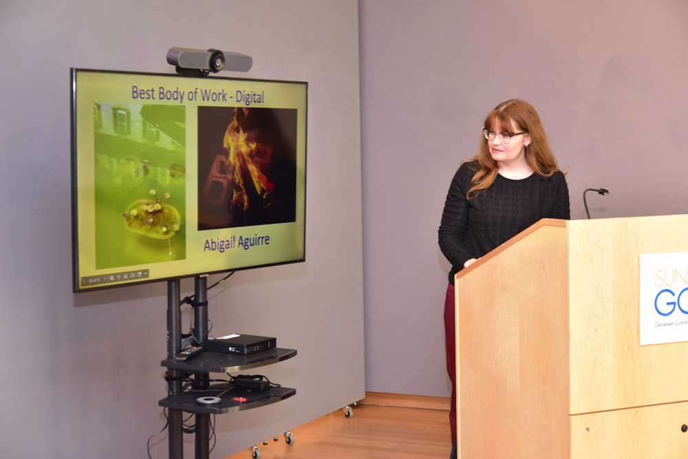 Presentation screen showing best body of work photos and woman at podium