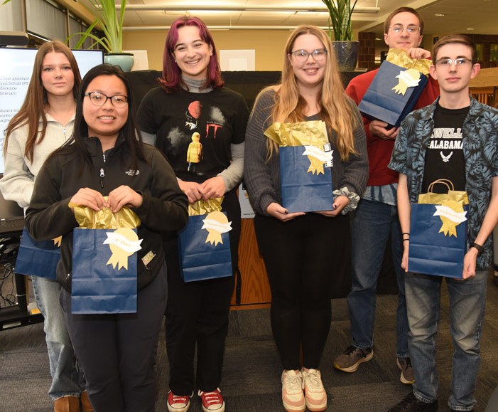 Six people standing together holding prize bags