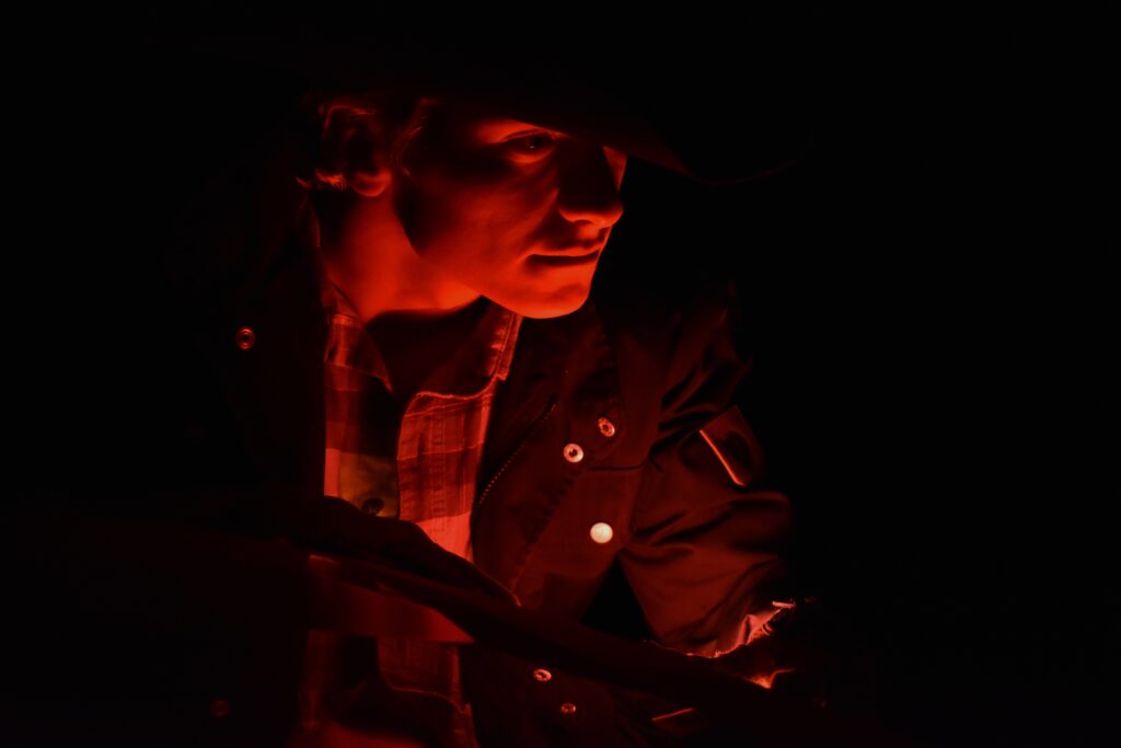 image of boy in hat with face lit in red light and dark background