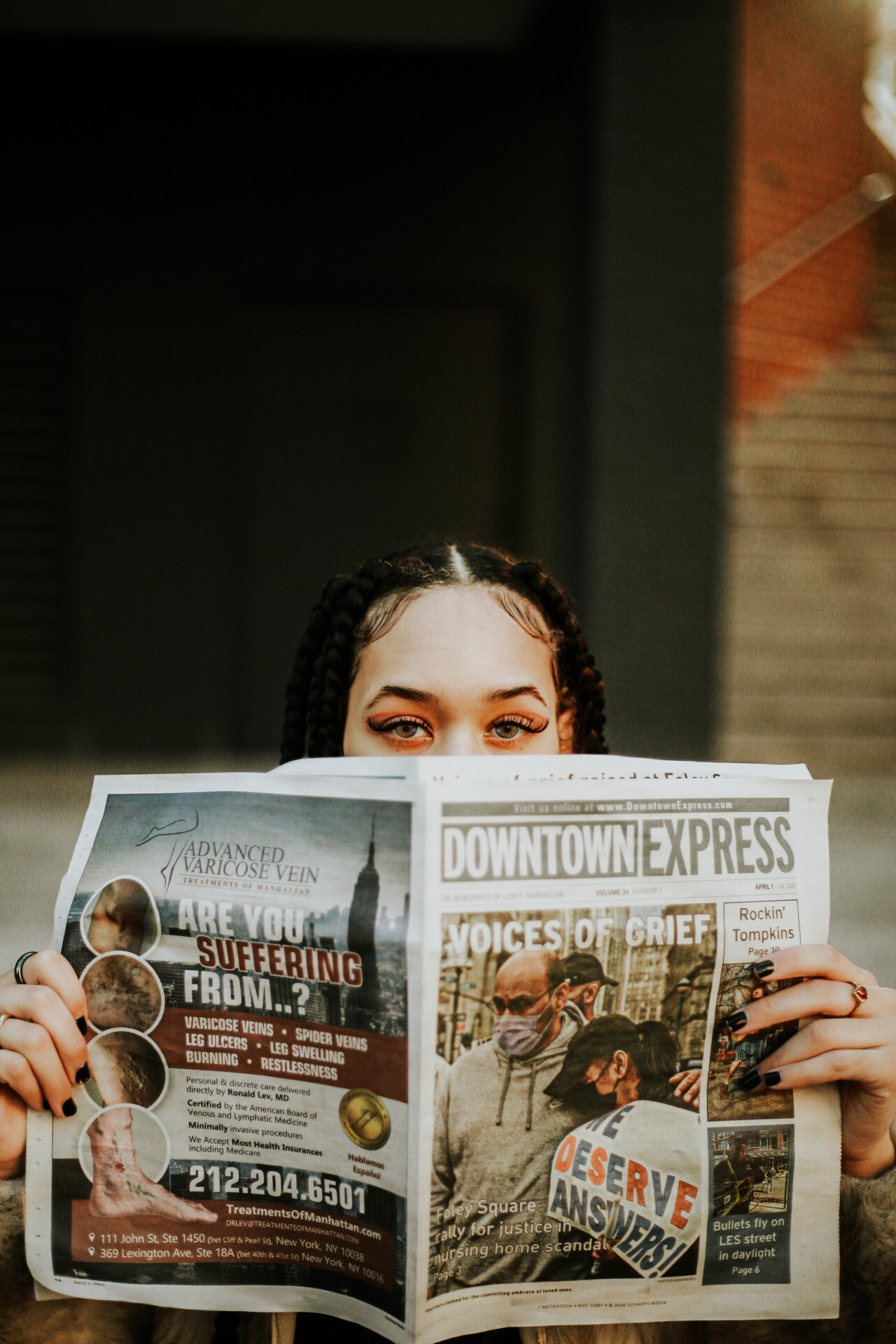 image of girl reading a newspaper and looking over the top