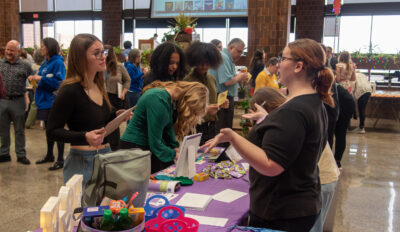 Students presenting to guests at a table at the Virtual Business Trade fair