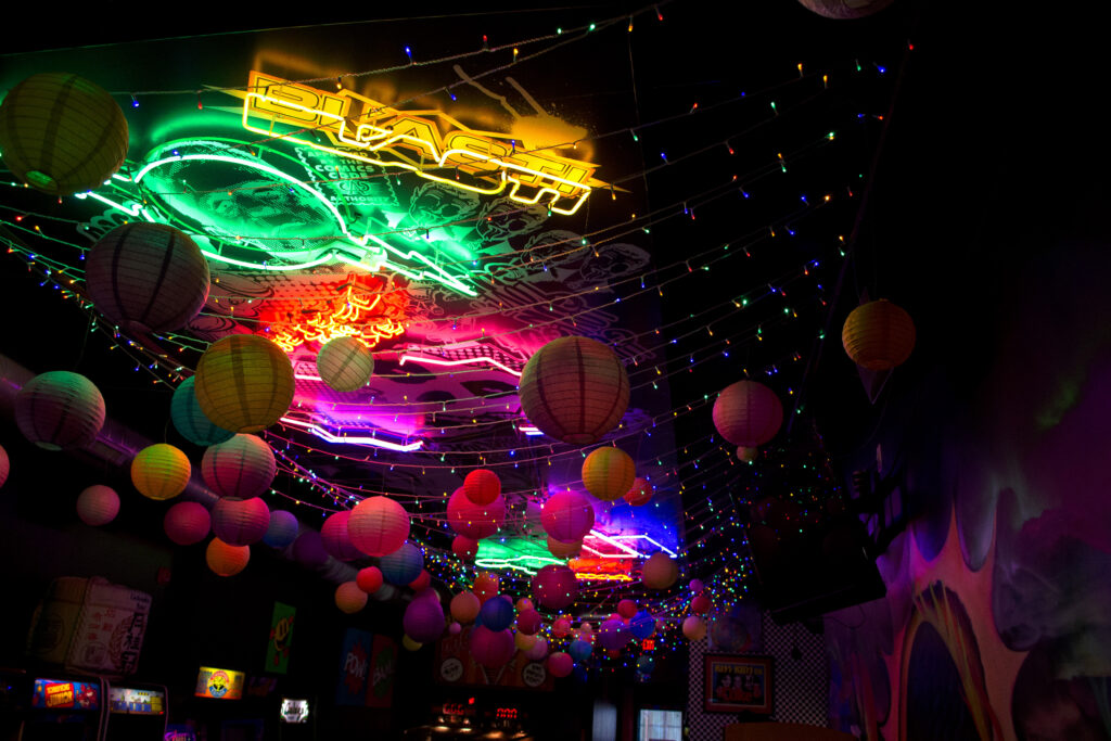 Photo of dark room with colorful lights and balloon lanterns hanging from ceiling