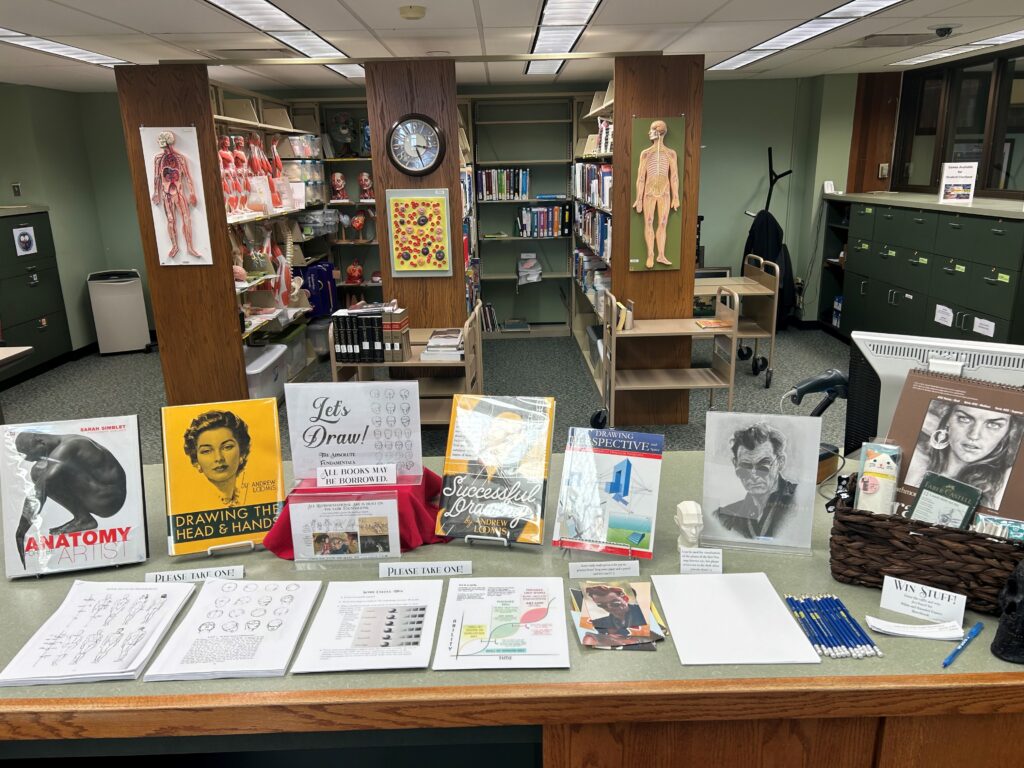 showing display of drawing books and instruction sheets at our circulation desk, with a gift basket to enter to win