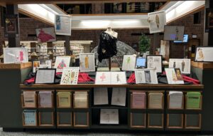display at library information desk showing framed fashion drawings and mannequin wearing black sequin top