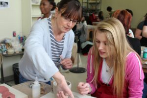 Ceramics student receiving guidance from a teacher.