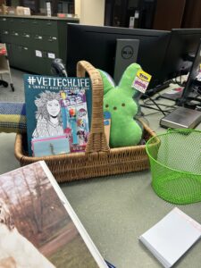 Basket with prizes including green stuffed peep, coloring book, cozy throw, pet-themed notepads, and more