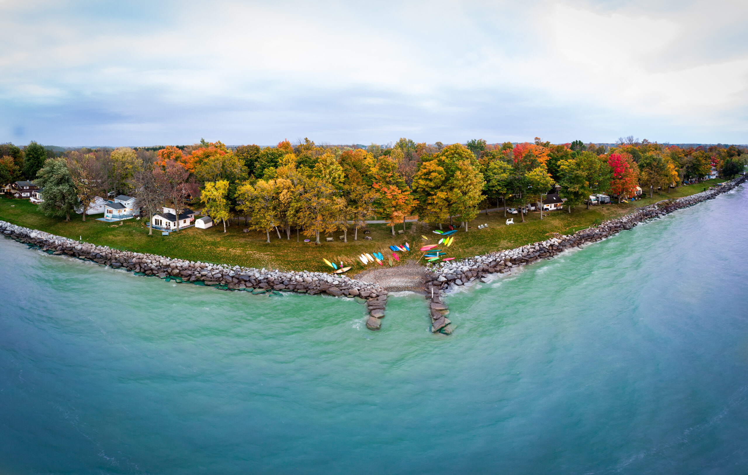 panoramic photo of vibrant lake/shore with autumn coloring in trees